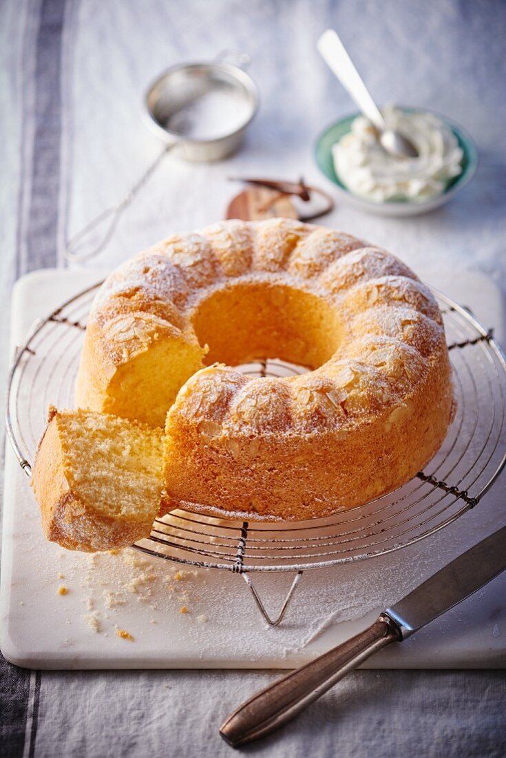 Napfkuchen mit Puderzucker, Mandelblättchen und Sahne, angeschnitten