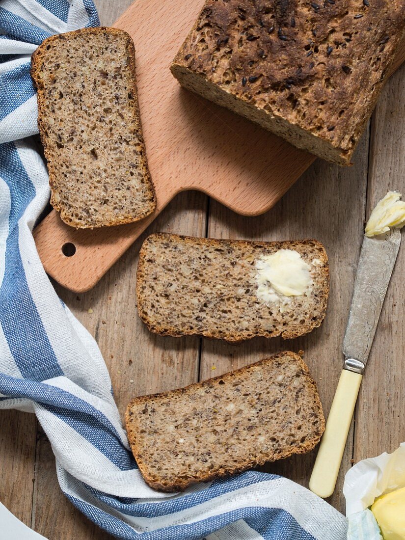 Wholemeal bread with flax seeds and sunflower seeds, one slice spread with butter