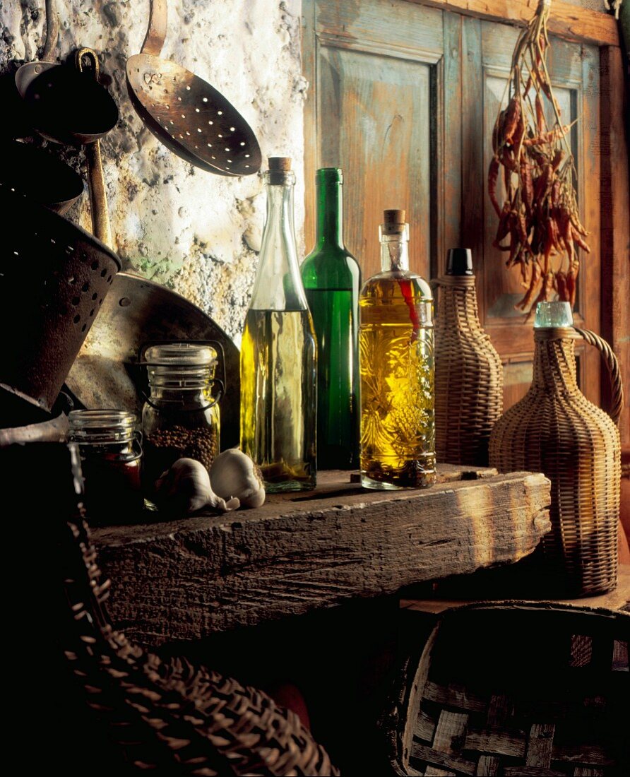 Bottles of oils, copper pots, jugs and spices in a rustic kitchen