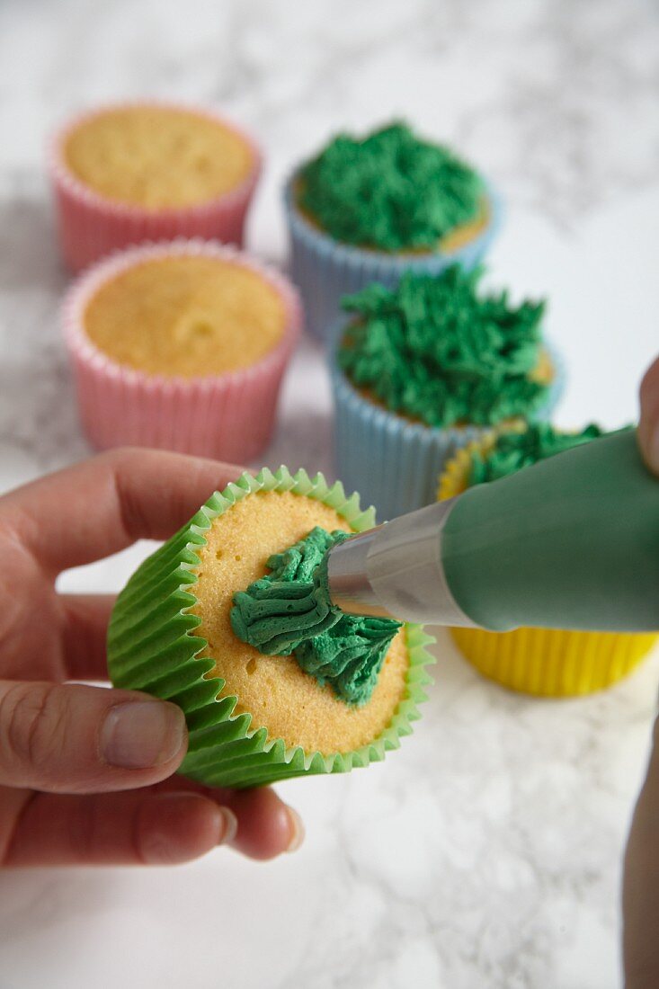 Easter cupcakes being made: green frosting being piped on