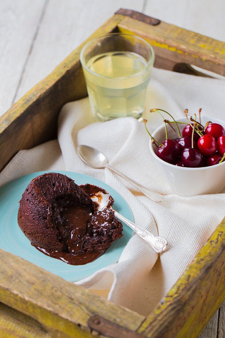 Warm chocolate lava cake, with fresh cherries and lemonade on a tray