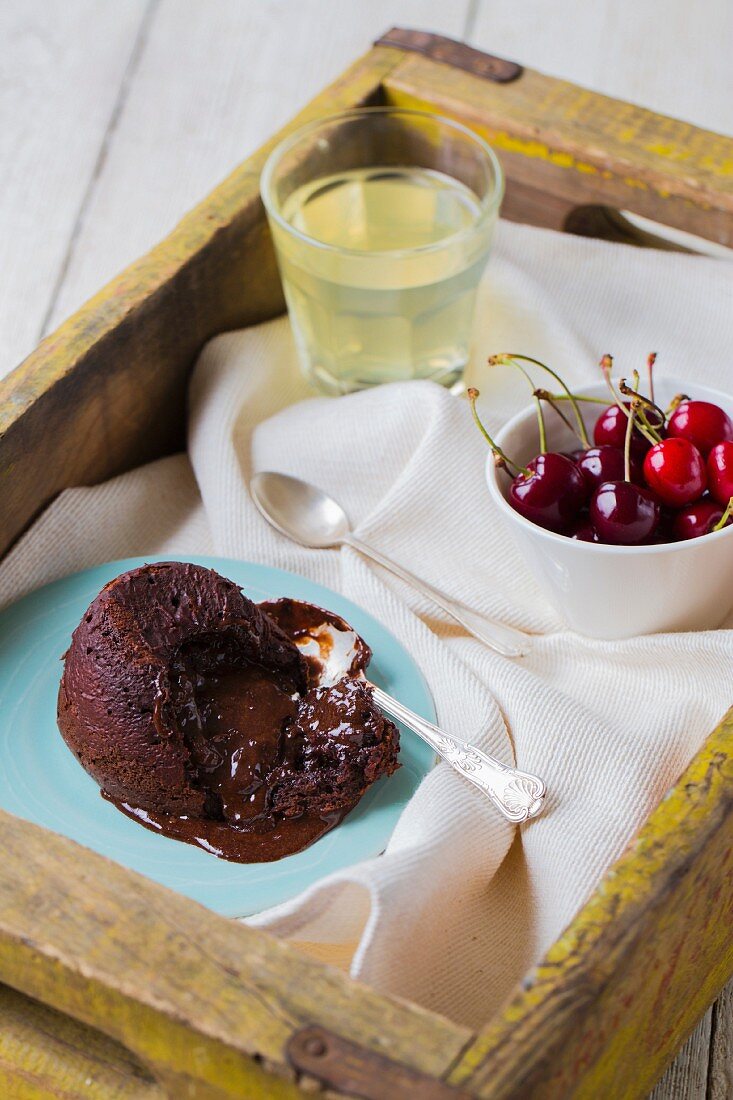 Warmer Schokoladenfondant, frische Kirschen und Limonade auf Tablett