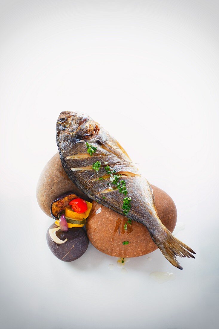 Baked seabream with vegetables on stones