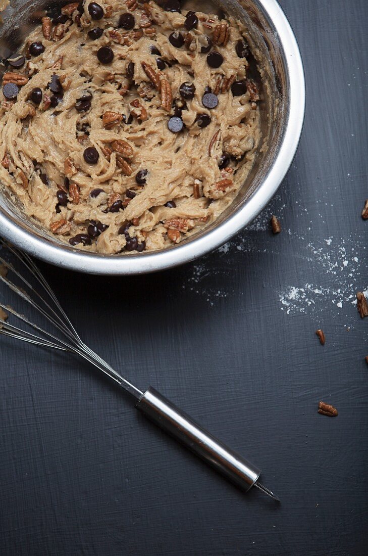 Chocolate chip cookie dough with pecan nuts in a mixing bowl