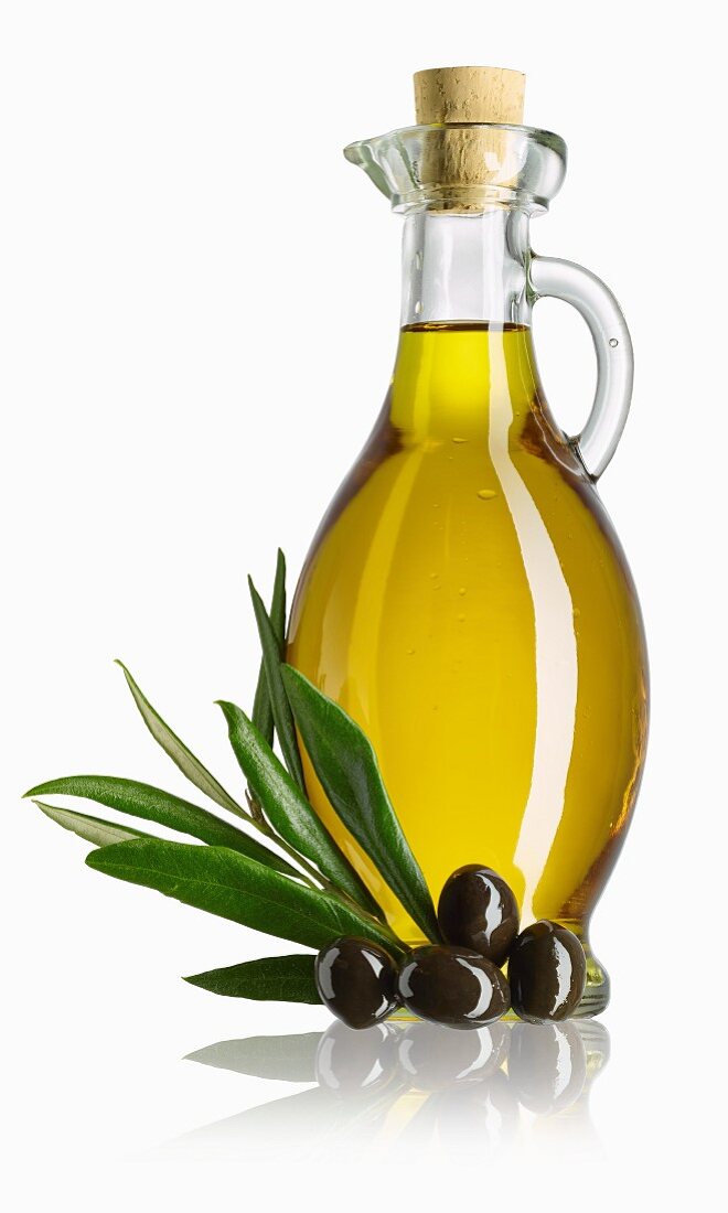 A carafe of olive oil, a sprig of olive leaves and black olives