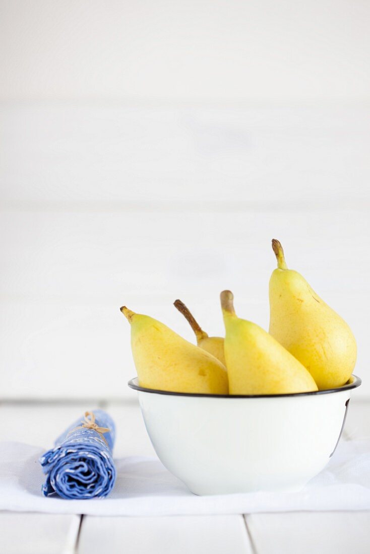 Four yellow pears in a bowl