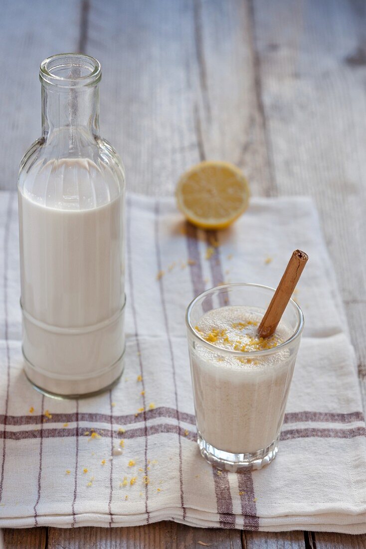 Almond milk with cinnamon and lemon zest in a bottle and a glass