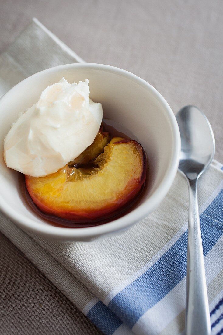 A honey-roasted peach with crème fraîche in a small white bowl