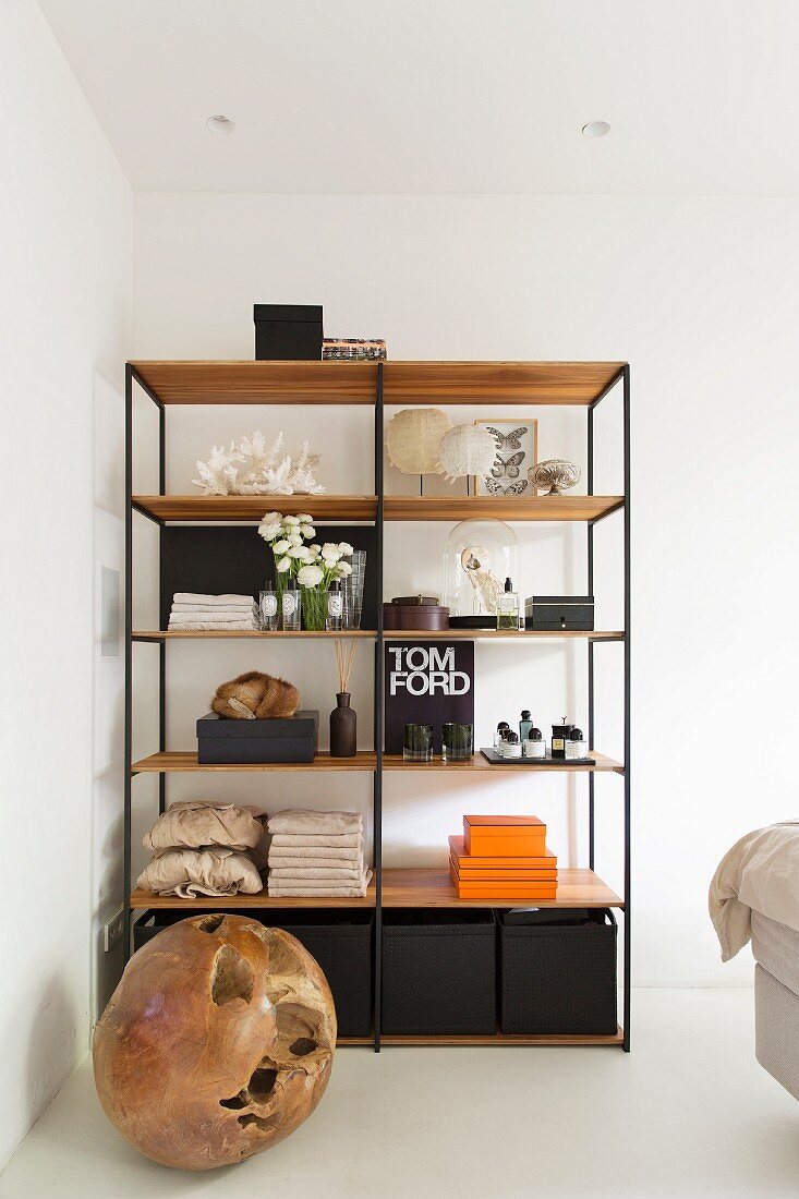 Wooden ball on floor in front of shelves with black metal frame and wooden shelves in corner of bedroom