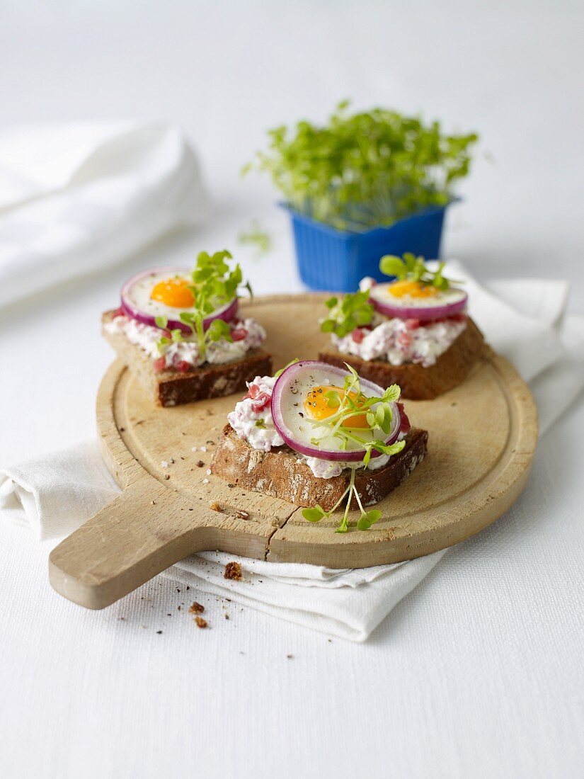 Slices of bread topped with ham salad, fried eggs and cress