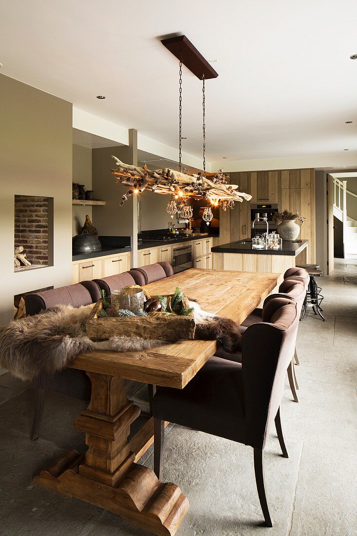 Rustic, solid-wood table and brown upholstered chairs in open-plan interior in various shades of brown