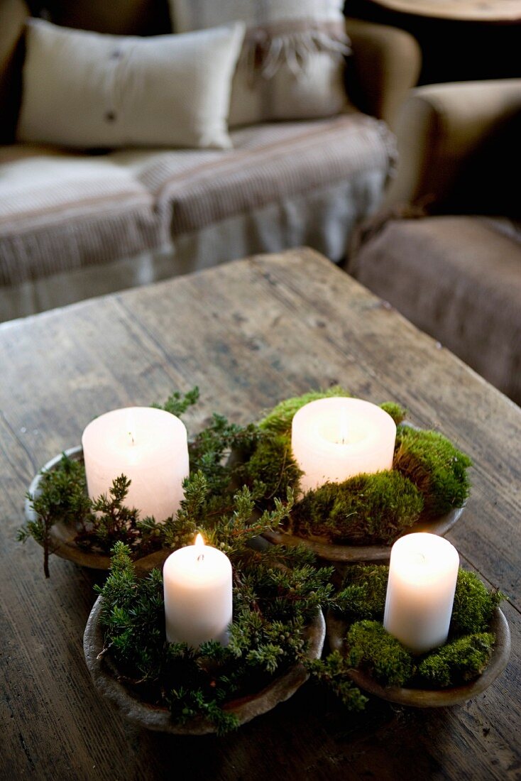 Candles arranged in wooden dishes of moss and small twigs