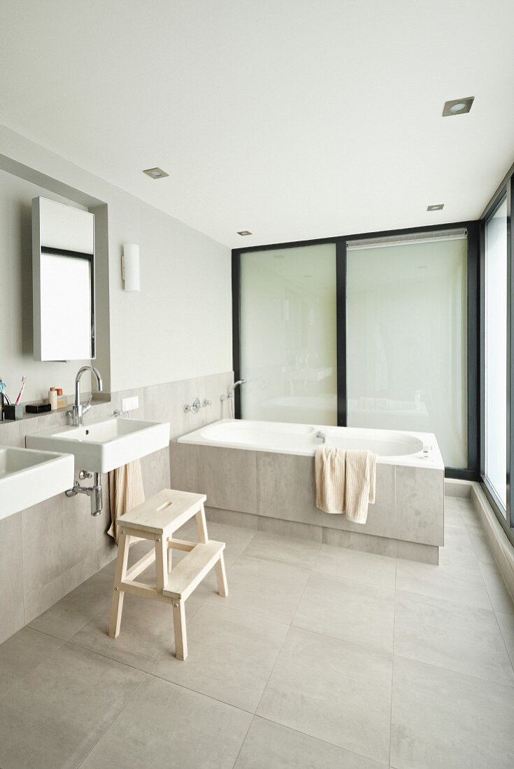 Minimalist designer bathroom with sinks below mirror in niche and bathtub