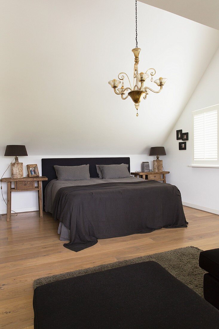 Double bed with dark headboard in elegant attic bedroom