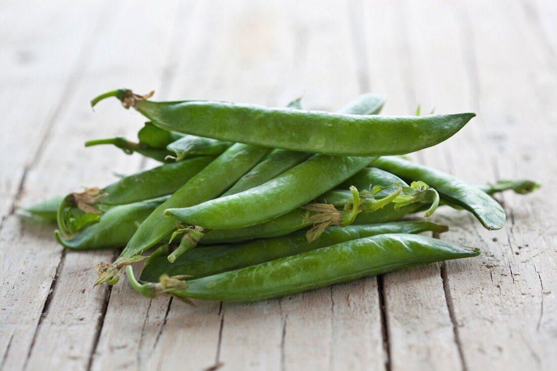 Fresh pea pods on a wooden surface