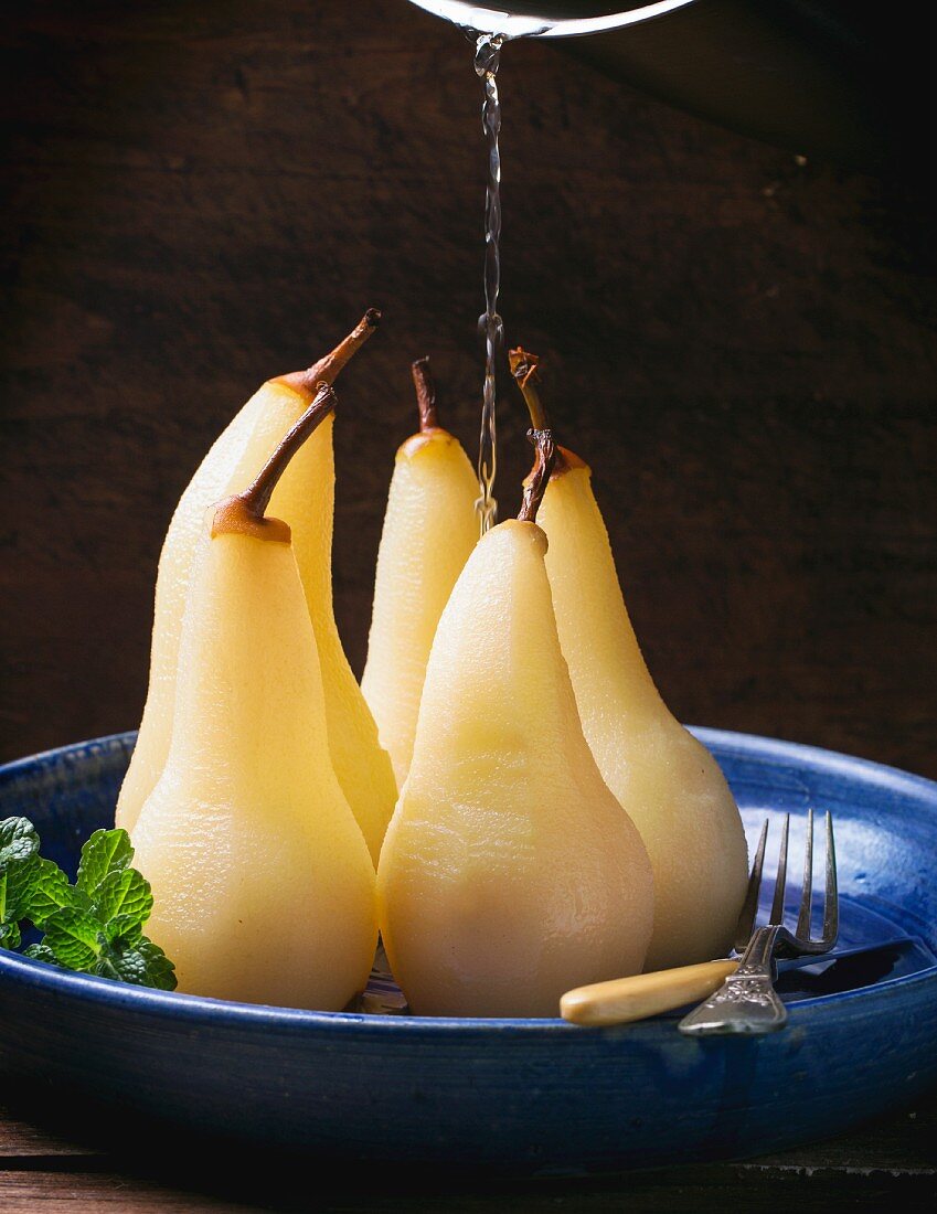 Syrup being poured over pears poached in white wine