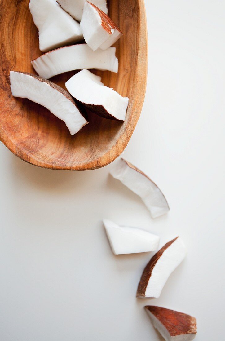 Coconut pieces in a wooden bowl and next to it