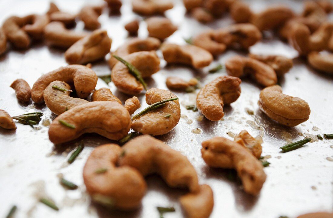 Cashew nuts with rosemary on a baking tray (close-up)
