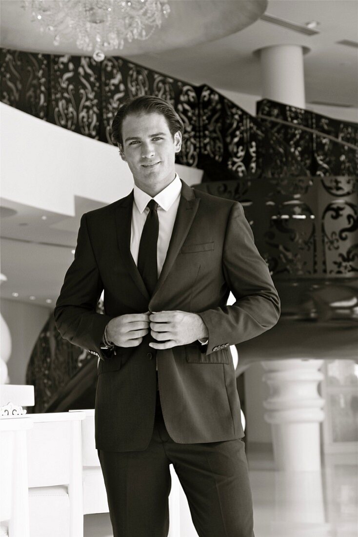 A young business man wearing a suit standing in an elegant hall