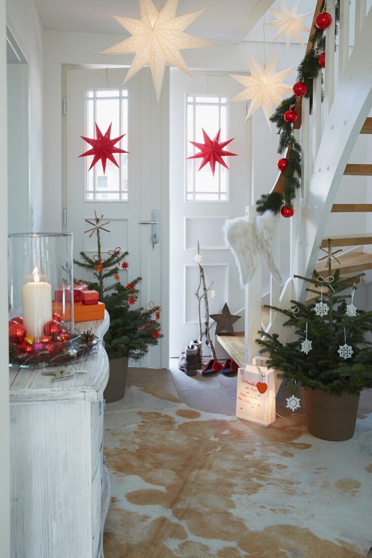 A hallway decorated for Christmas with decorated trees and garlands on the banister