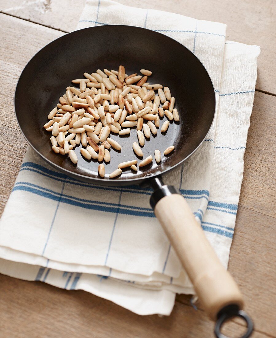 Pine nuts being dry roasted in a pan