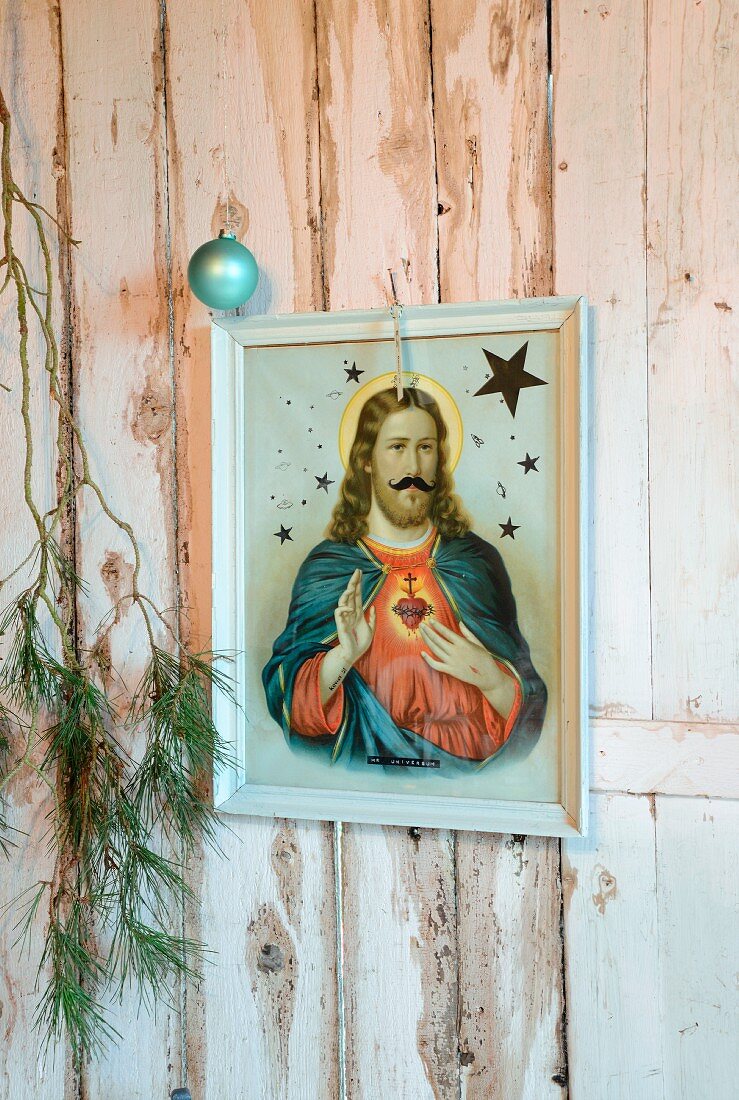 Framed icon, fir branches and Christmas bauble on white, rustic wooden wall