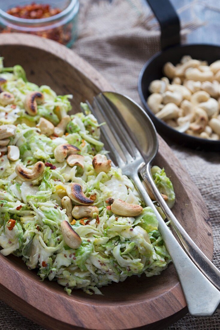 Brussels sprouts salad with roasted cashew nuts in a wooden bowl