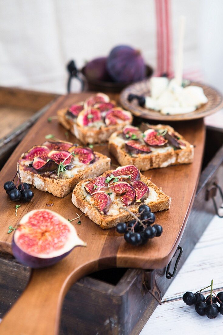 Gorgonzola sandwiches with figs and grapes on a wooden chopped board