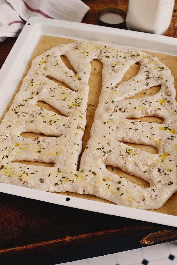 Unbaked fougasse with bacon and walnuts on a baking tray
