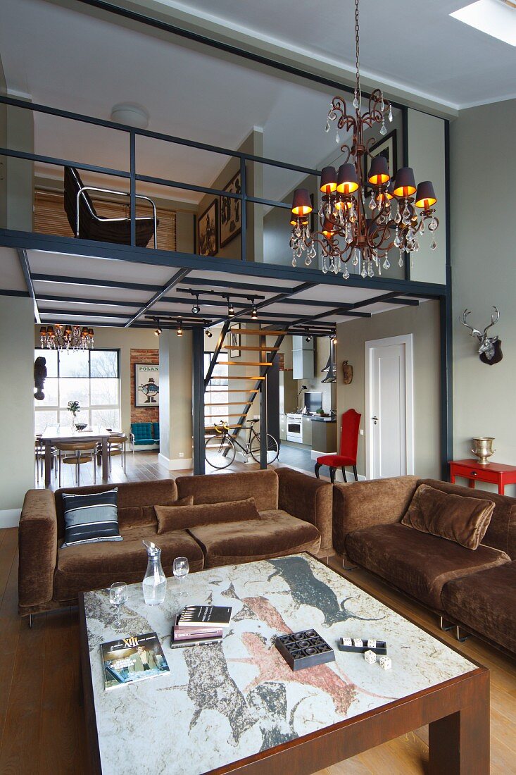 Coffee table with picture engraved on stone top and brown, velvet sofa set in open-plan interior with mezzanine