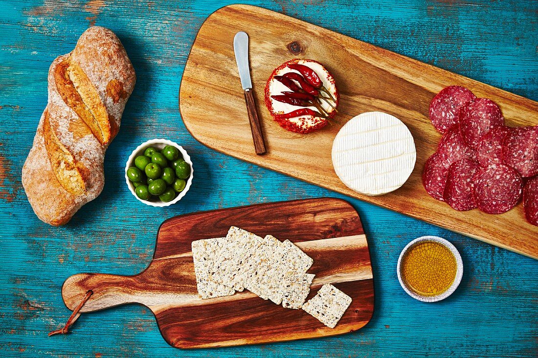 Holzplatte mit Antipasti (Salami, Käse, Cracker, Brot und Oliven)