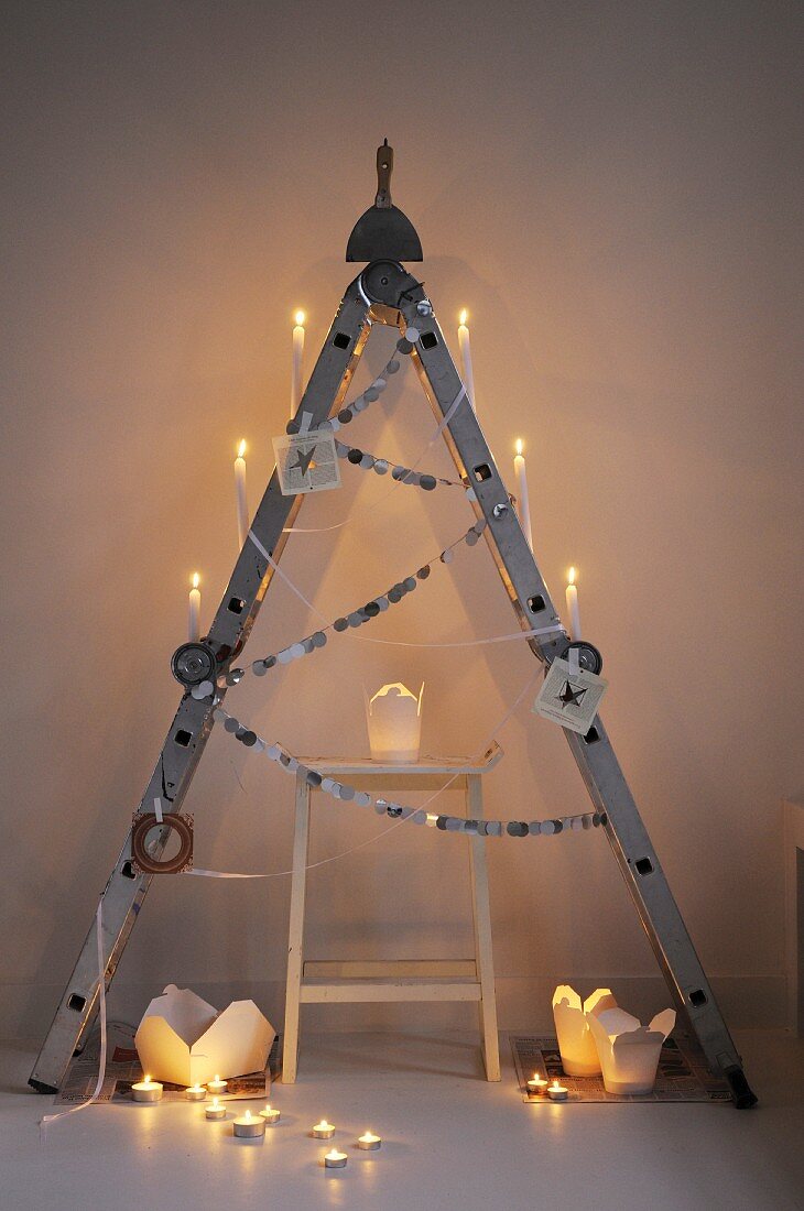 Alternative Christmas tree made from folding ladder and take-away cartons used as candle lanterns