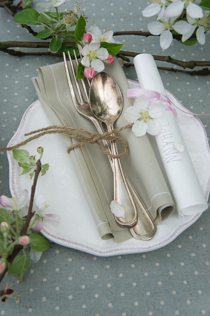 A place setting decorated with apple blossom and a place card