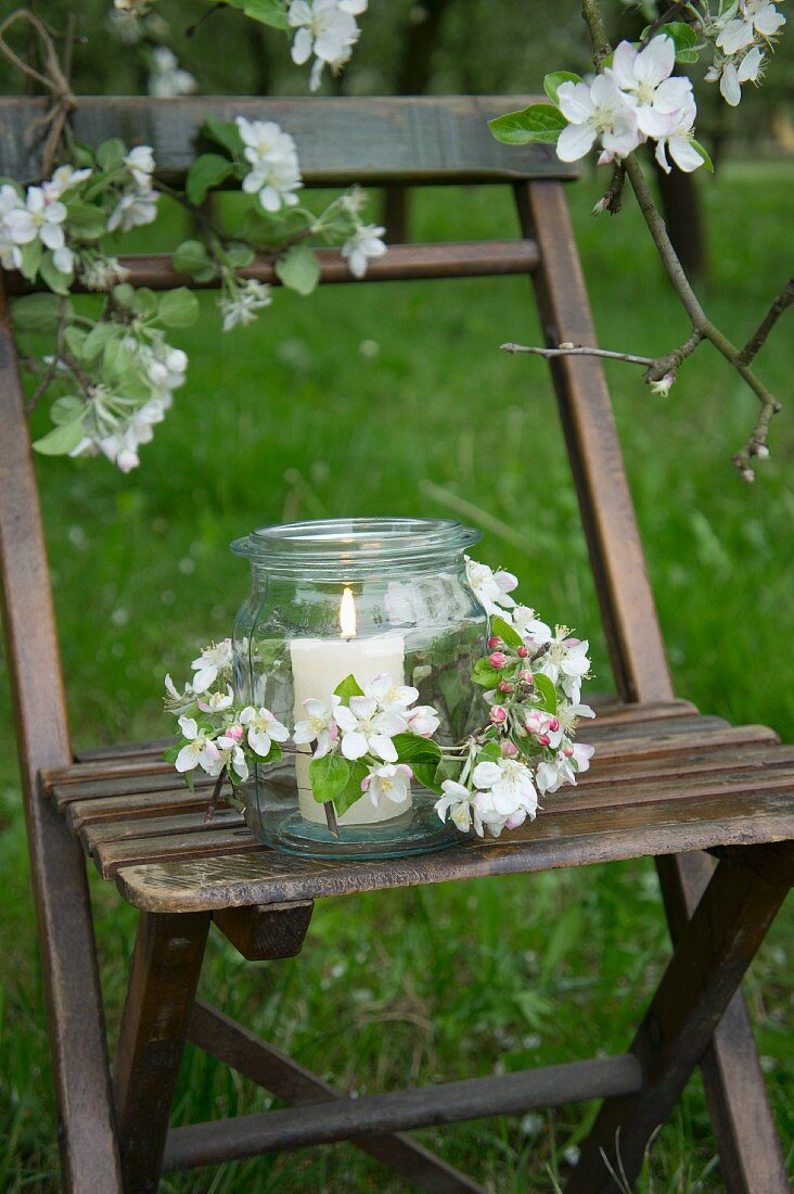 A candle holder on a chair decorated with apple blossom