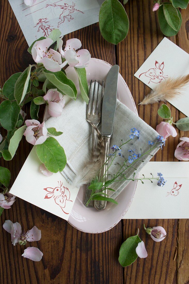 Silver cutlery, flowers and Easter place cards in dish