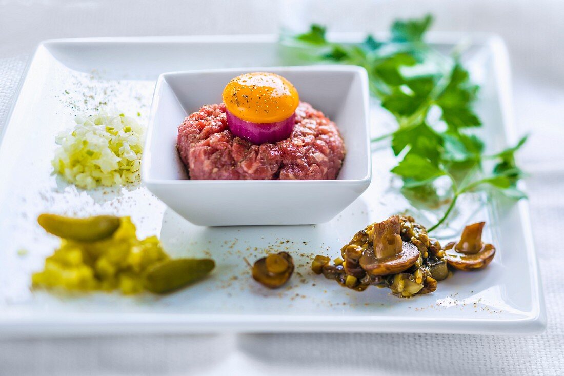 Beef tartare with red onion, egg yolk and sides