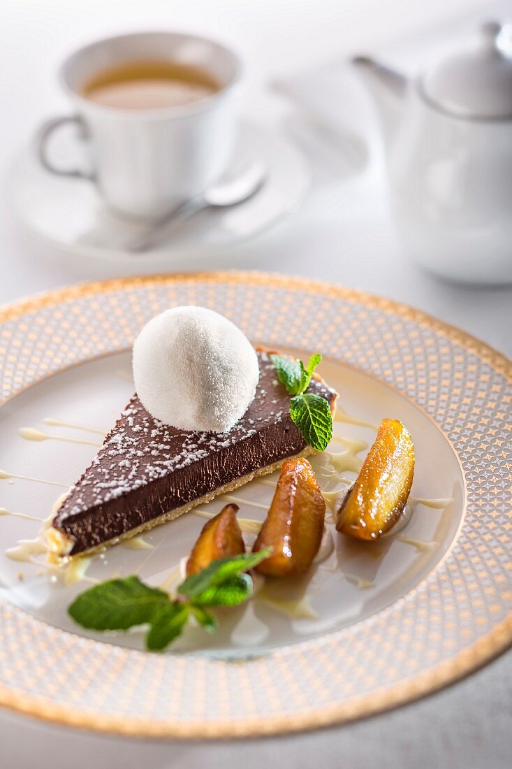 Chocolate tart with creme anglaise, pears and a scoop of milk ice cream on a festive plate