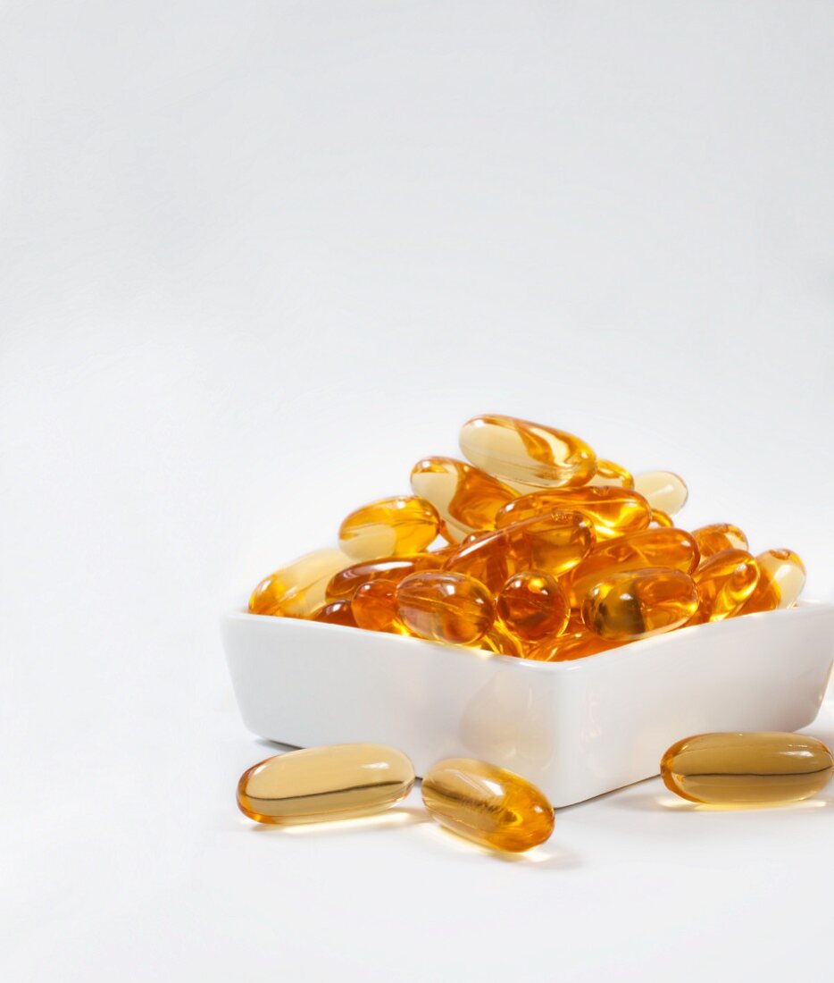 Fish oil capsules in a porcelain bowl against a white background