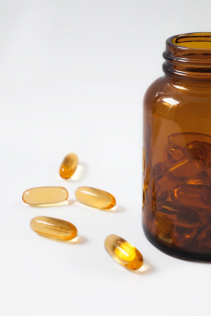 Fish oil capsules next to and in a bottle