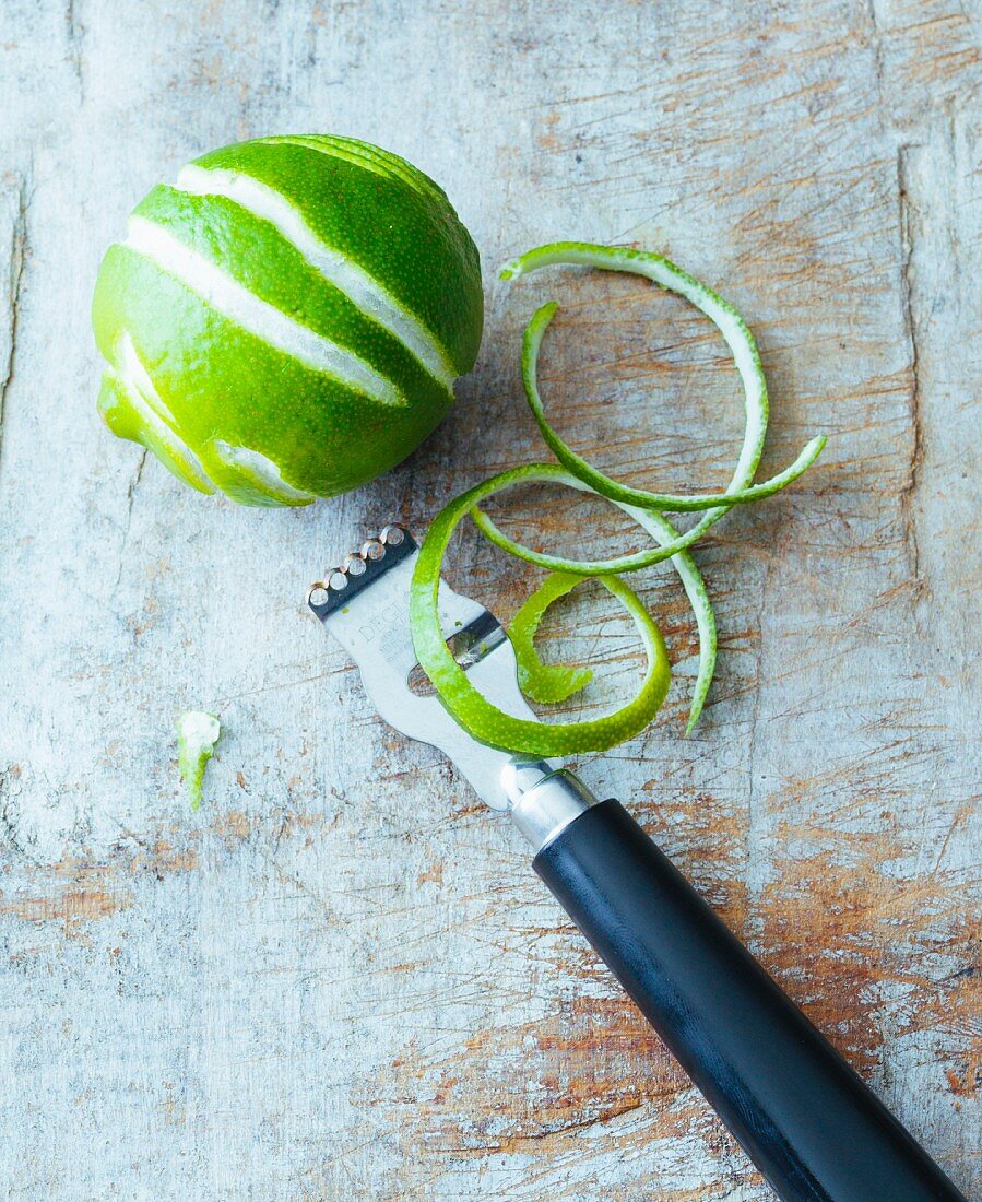 A lime with zest and a zest peeler