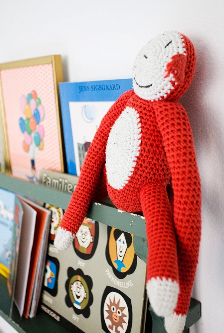 Crocheted toy monkey and books on shelf