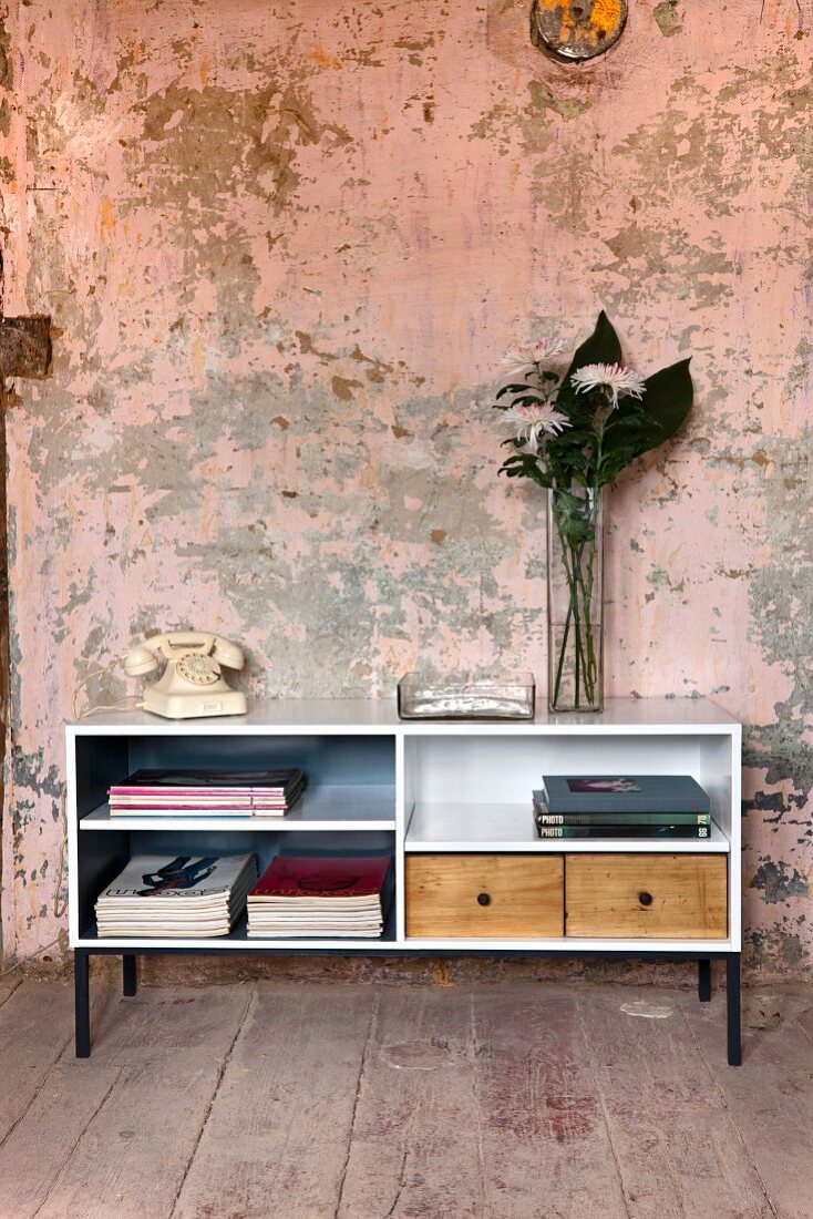 Upcycling - Offenes Sideboard weiss lackiert mit Holz Schubladen, vor Wand mit abblätternder Farbe