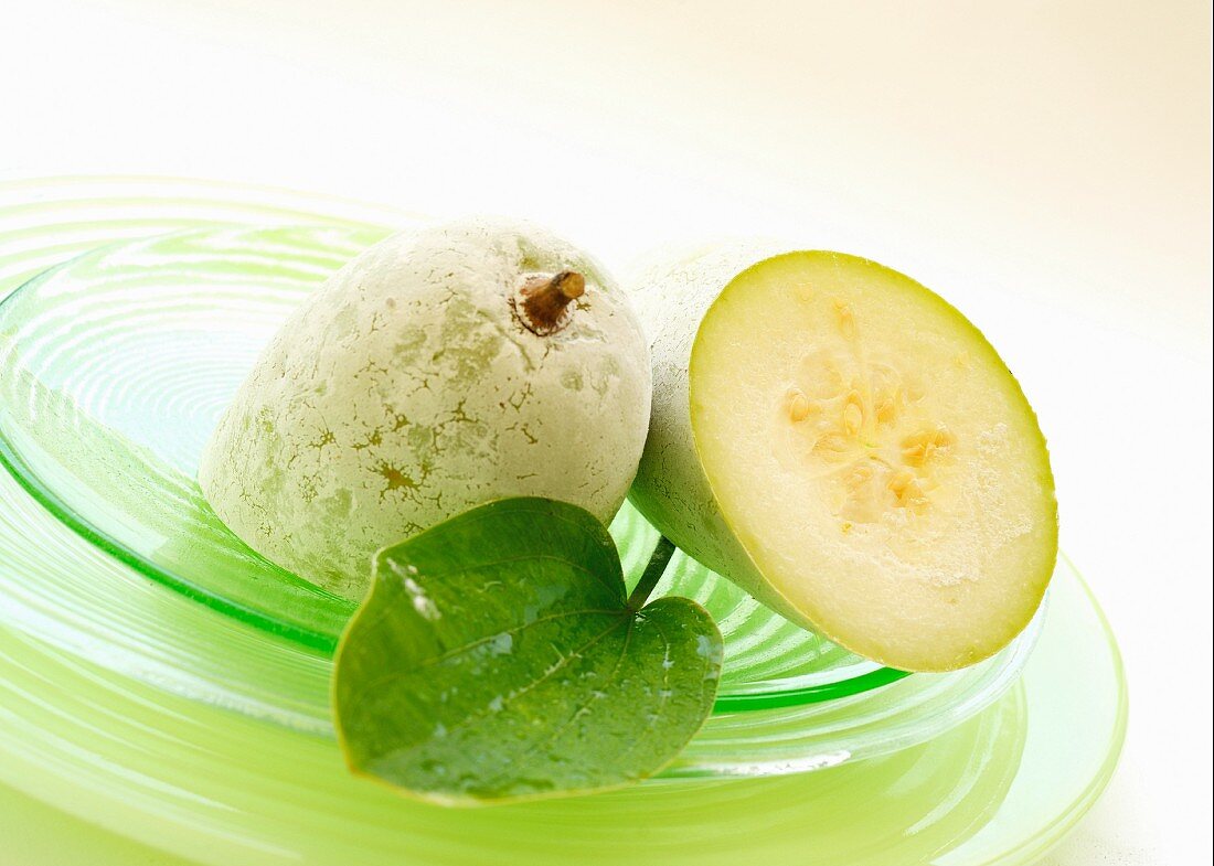 A halved fuzzy melon on a glass plate