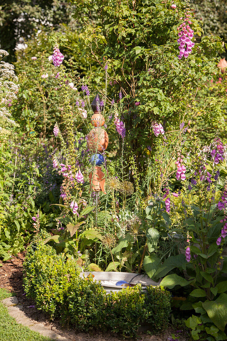 Pink foxgloves and garden ornaments in idyllic garden