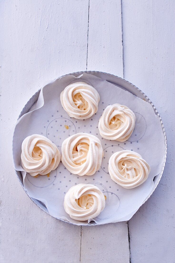 Meringues on a plate lined with baking paper (seen from above)