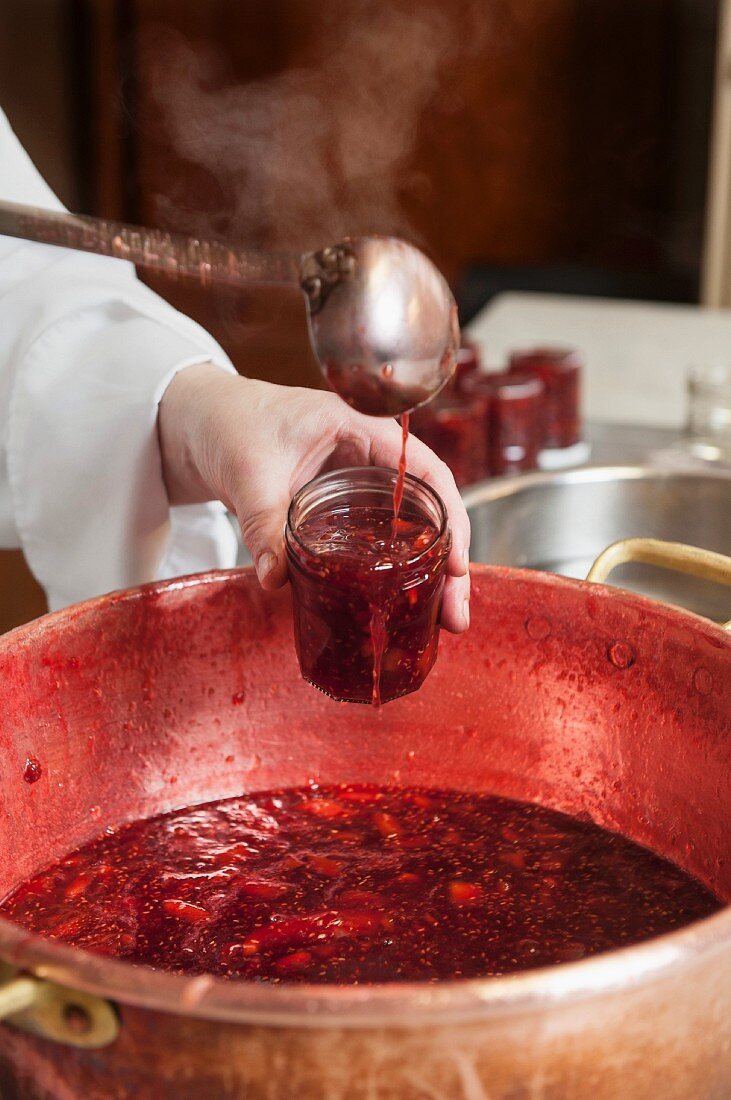 Noch heiße Marmelade in Gläser abfüllen