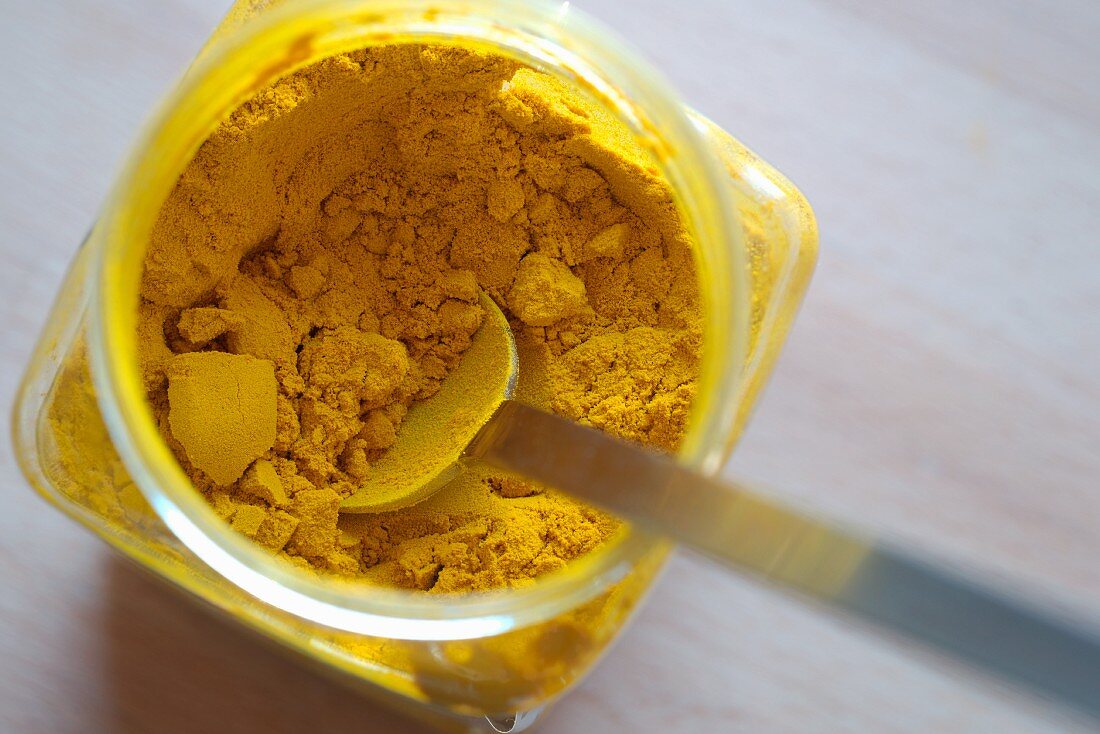 Turmeric powder in a jar with a spoon