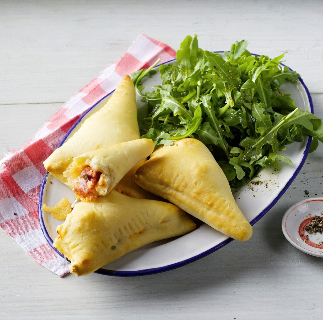 Pizza pockets filled with salami and sardines served with fresh rocket