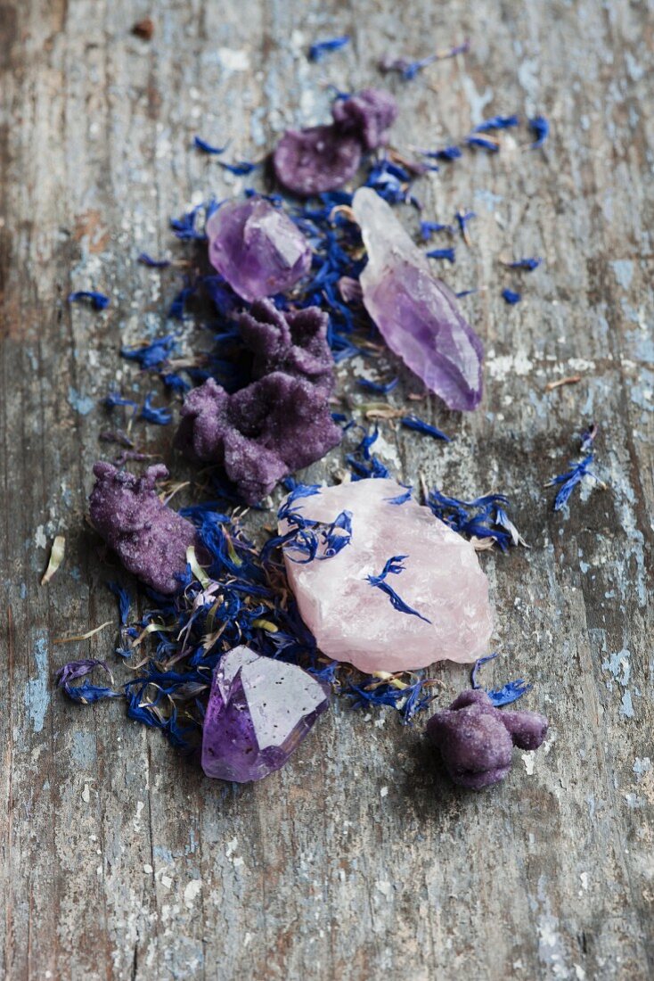 Healing stones, cornflour leaves and candied violet on a wooden surface