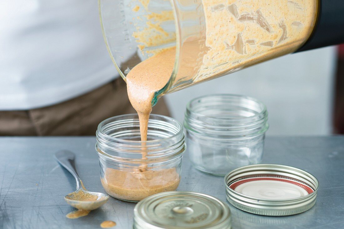 Almond and macadamia mousse being poured into screw-top jars